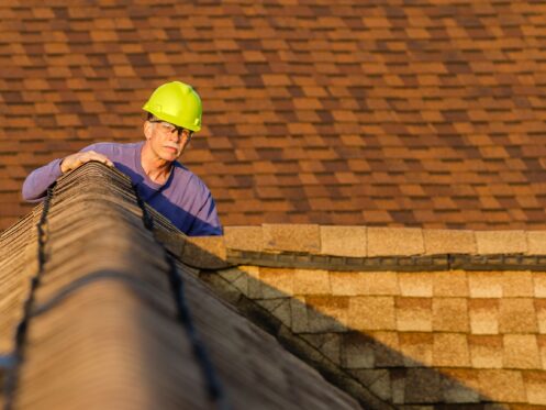 An inspector looks over a residential roof at the peak.